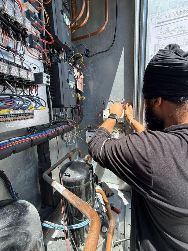 Jagdeep Singh, founder of PowerLogic, terminating wiring at a rooftop unit control panel
