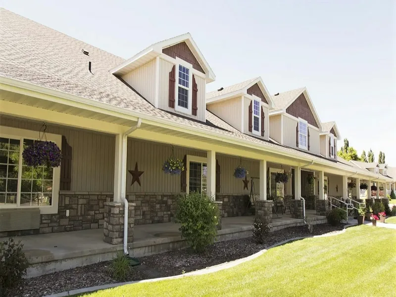 Single-storey seniors' residence with a long covered porch, dormer windows, accessible ramps and a landscaped lawn