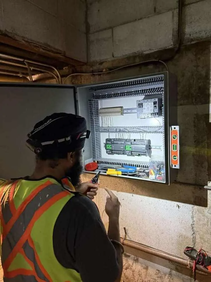 Technician checking a newly installed building automation control panel